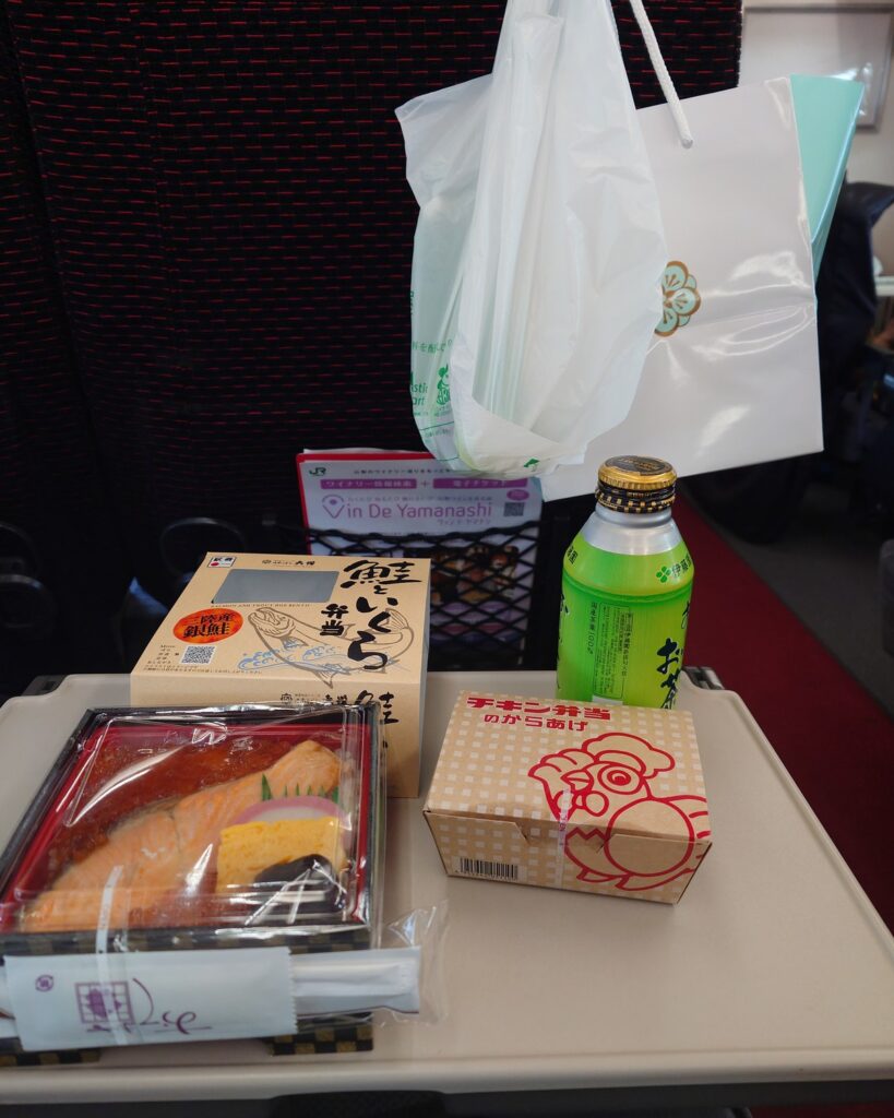 長野へ帰る電車内で、座席のテーブルに駅弁とお茶を並べたところ。